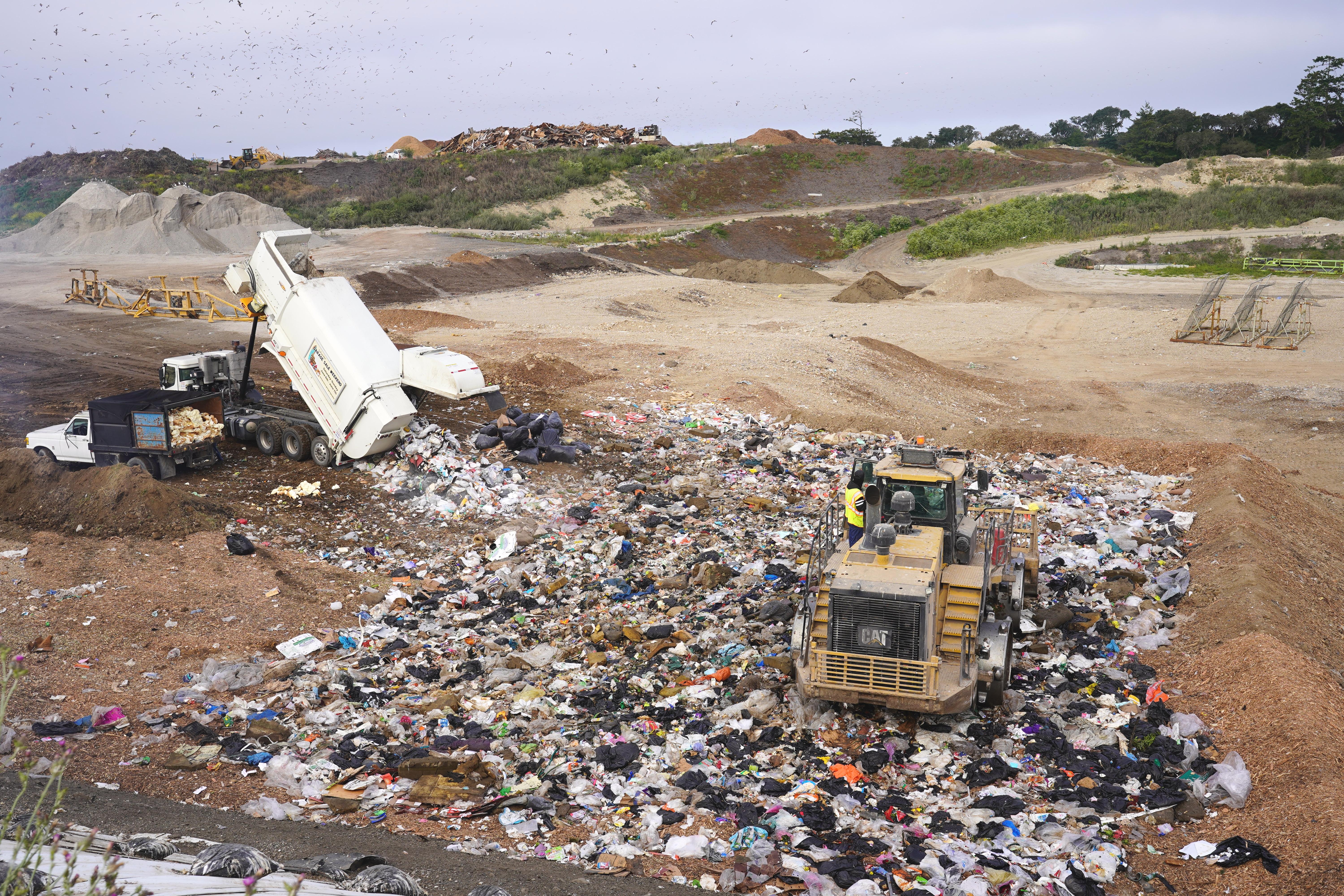 Garbage truck dumps its load at the active landfill cell
