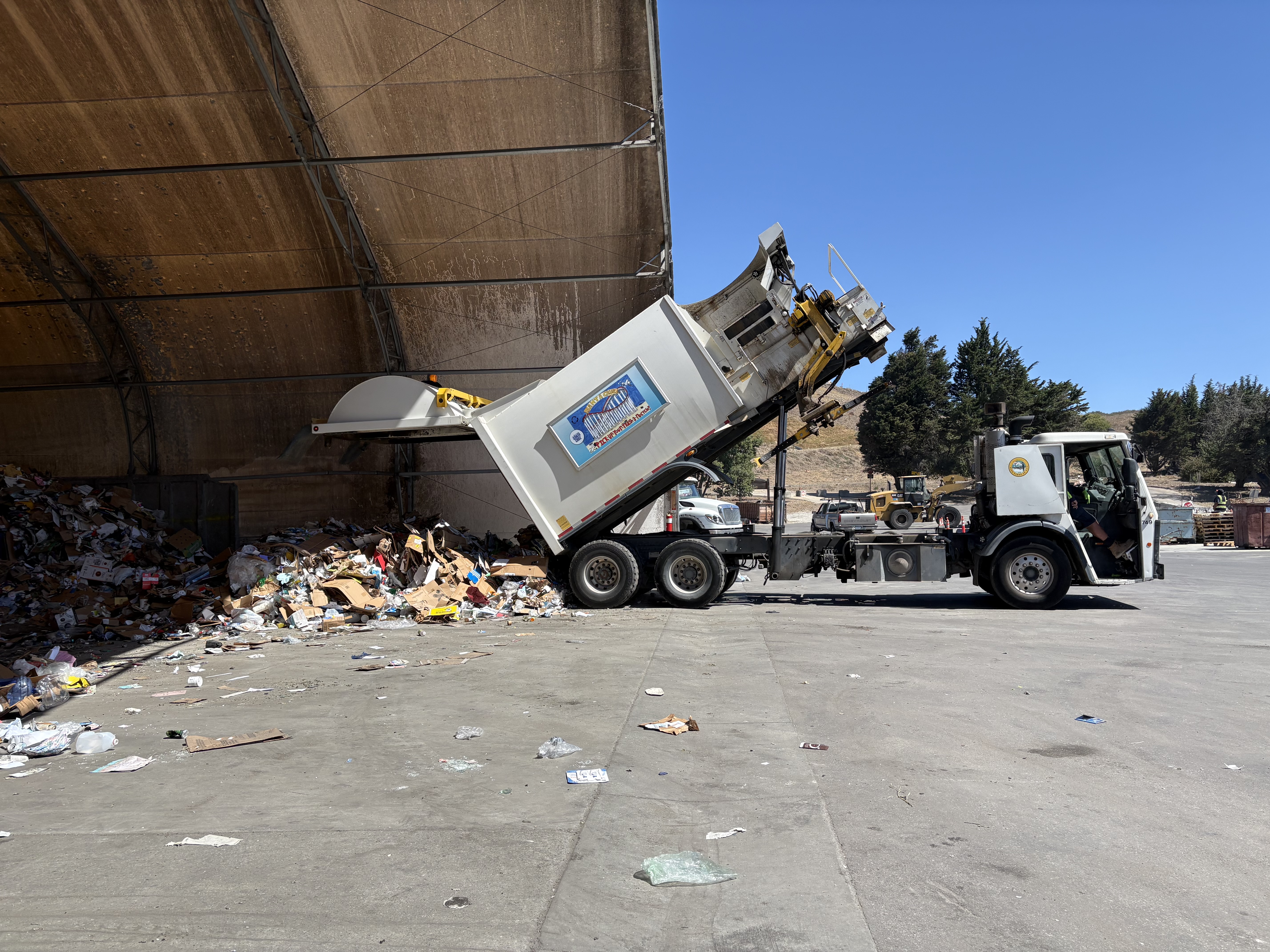 A recycling truck dumps its load onto the tipping floor